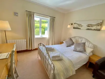 a bedroom with a bed and a desk and a window at Llety Ceiro Guesthouse in Aberystwyth