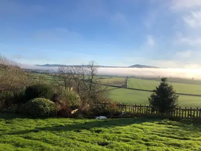 a view of a field with a fence and a foggy valley at The View in Welshpool