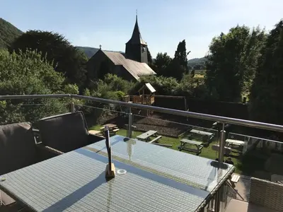 a table on a balcony with a view of a church at Grapes Hotel, Bar & Restaurant Snowdonia Nr Zip World in Blaenau-Ffestiniog