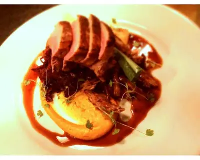 a white plate of food with meat and sauce at Seabreeze Restaurant With Rooms in Aberdyfi
