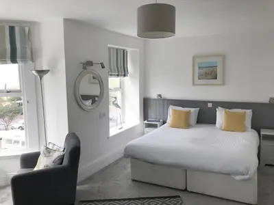a bedroom with a bed and a chair and a mirror at Seabreeze Restaurant With Rooms in Aberdyfi