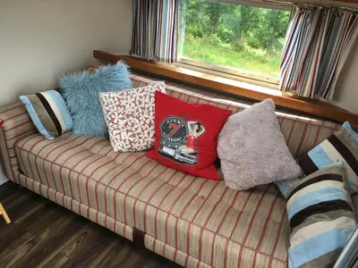 a couch with pillows on it with a window at Ludlow Vintage Airstream in Ludlow