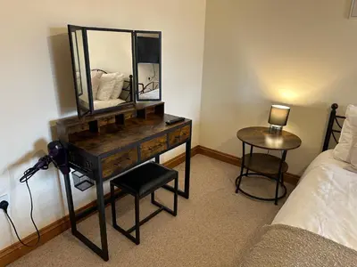 a bedroom with a dresser with a mirror and a bed at Riverside in Brecon