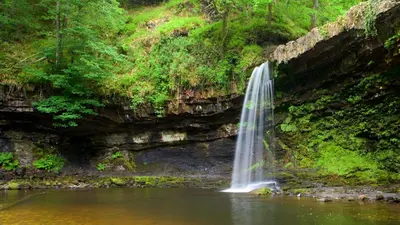 a waterfall in the middle of a body of water at Riverside in Brecon