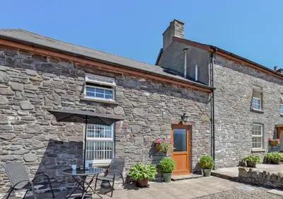 a stone house with a table and an umbrella at 1 Bed in Nantygwreiddyn oc-bow49 in Sennybridge