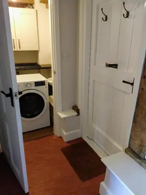 a laundry room with a washing machine and a door at Little Drift in Edgton