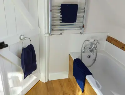 a bathroom with a tub and a shower with blue towels at Little Drift in Edgton