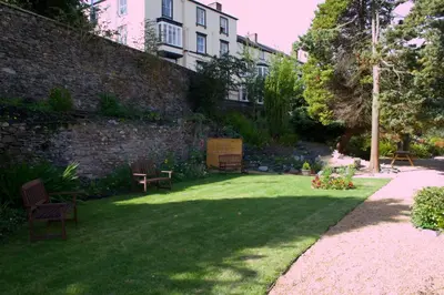 a garden with benches and a brick wall at The Hand Hotel Llangollen by Compass Hospitality in Llangollen