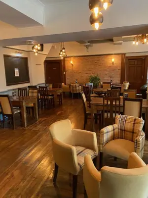 a restaurant with wooden floors and tables and chairs at The Hand Hotel Llangollen by Compass Hospitality in Llangollen