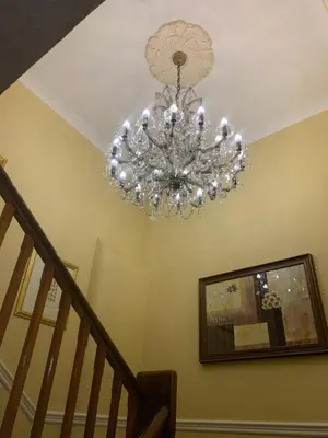 a chandelier hanging from a ceiling with a staircase at The Hand Hotel Llangollen by Compass Hospitality in Llangollen