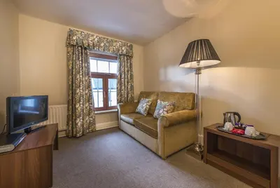 a living room with a couch and a television at The Royal Oak Hotel, Welshpool - The Coaching Inn Group in Welshpool