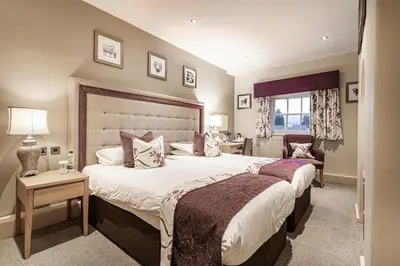 a large bedroom with two beds and a desk at The Royal Oak Hotel, Welshpool - The Coaching Inn Group in Welshpool