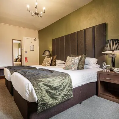 a bedroom with a large bed with a large headboard at The Royal Oak Hotel, Welshpool - The Coaching Inn Group in Welshpool