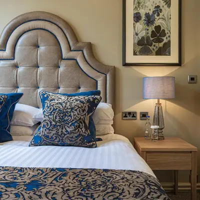 a bedroom with a large bed with a blue and white pillow at The Royal Oak Hotel, Welshpool - The Coaching Inn Group in Welshpool