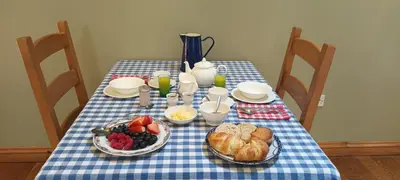 a table with a blue and white checked table cloth with bread and fruit at Henllys Estate B and B in Llandovery