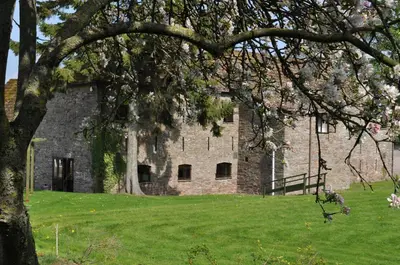 an old stone building with a tree in the foreground at Black Mountain Lodge in Glasbury
