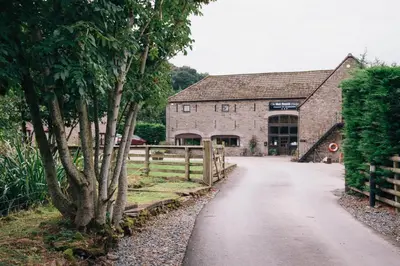 a road leading to a stone building with a fence at Black Mountain Lodge in Glasbury