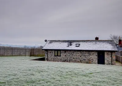 a stone house in a field with a yard at Smithy Cottage in Berriew