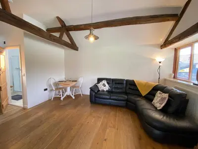 a living room with a black leather couch and a table at Smithy Cottage in Berriew