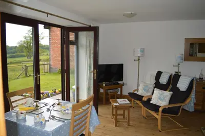 a living room with a table and chairs and a television at Smithfield Farm Bed & Breakfast in Builth Wells