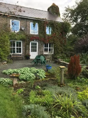 a garden in front of a brick house at Pen y Crug Cottage in Llanafan-fawr