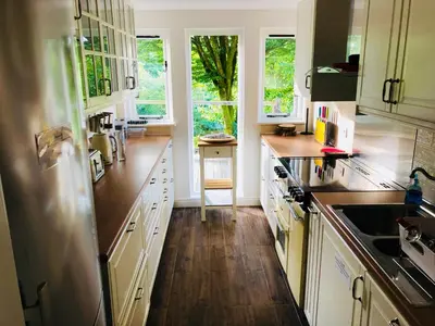 a kitchen with white cabinets and wooden floors and windows at Llethrau Forest & Nature Retreats in Knighton