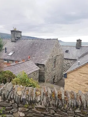 an old stone house with a stone fence in front of it at Penbryn Holidays, Barmouth in Barmouth