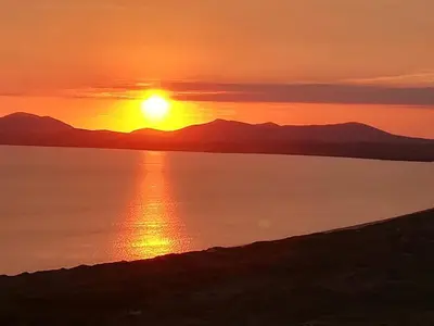 a sunset over the water with mountains in the background at Cadwgan House in Dyffryn