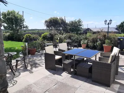 a patio with a table and chairs and plants at Cadwgan House in Dyffryn