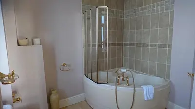 a bath tub in a bathroom with a shower at Cadwgan House in Dyffryn