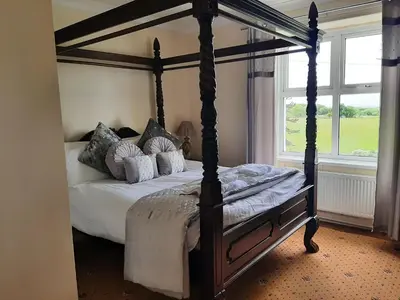 a bedroom with a canopy bed with pillows at Cadwgan House in Dyffryn
