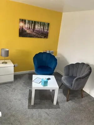 a living room with a blue chair and a table at Winforton B&B in Winforton