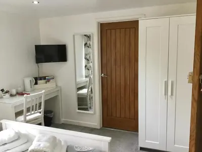 a room with a door and a desk with a mirror at Winforton B&B in Winforton