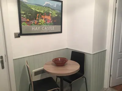 a small table and chairs in a room with a picture on the wall at The Flat Frank Lewis House in Hay-on-Wye