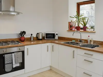 a kitchen with white cabinets and a sink at Y Gweithdy in Barmouth