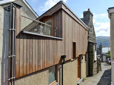 a wooden building with a window on a street at Y Gweithdy in Barmouth