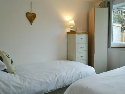 a bedroom with two beds and a dresser and a window at Lle Clyd in Harlech