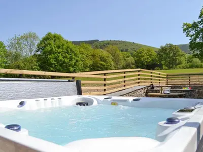 a hot tub on a patio with a fence at Bryn Salem in Mallwyd