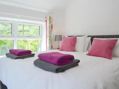 a white bed with pink pillows on top of it at Bryn Salem in Mallwyd