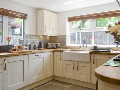 a kitchen with white cabinets and a sink and windows at Bryn Salem in Mallwyd