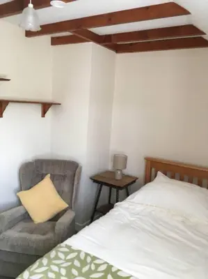 a bedroom with a bed and a chair and a pillow at Canol y Llan in Machynlleth