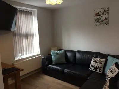 a black leather couch in a living room with a window at Swyn y Mor beach close Pet friendly hot tub in Barmouth