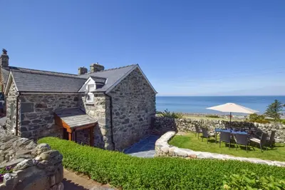 a stone building with a table and chairs and an umbrella at 2 Bed in Barmouth oc-bow52 in Llanaber