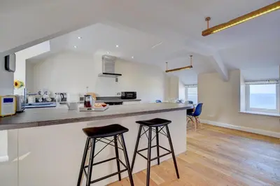 a kitchen with two bar stools at a counter at 2 Bed in Barmouth oc-bow52 in Llanaber