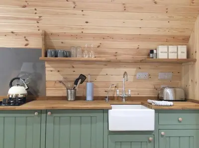 a kitchen with a sink and a counter with wooden walls at Cil y Coed Luxury Pod in Machynlleth