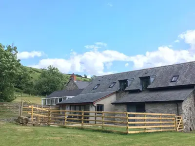 a barn with a wooden fence in front of it at Ty Glo Cottage in Brecon