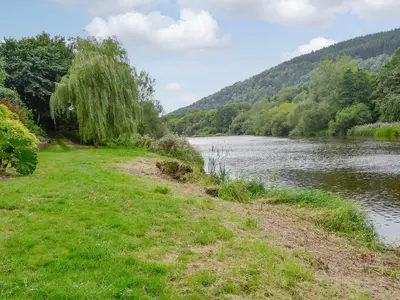 a grassy field next to a body of water at Wye Lodge in Aberedw