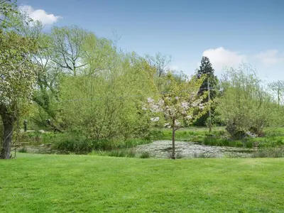 a park with a pond and trees and a river at The Cart Shed in Kings Pyon