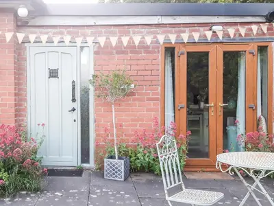 a brick house with a white door and a table at Mortimer Trail Mews in Aymestrey