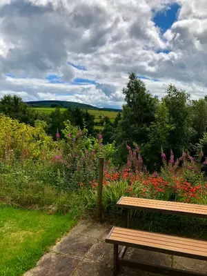 a wooden bench sitting in front of a field of flowers at The Granary Country Retreat in Lampeter